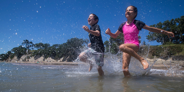 Billy Brown, 9, left, and Ellie Brown, 12, (brother and sister) crash into the water to beat the hot weather at Narrow Neck Beach. Photo / Jason Oxenham