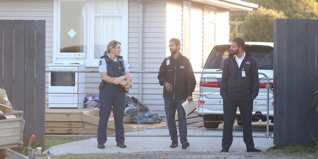 Police and security stand outside a house in Waiuku. Photo / NZME