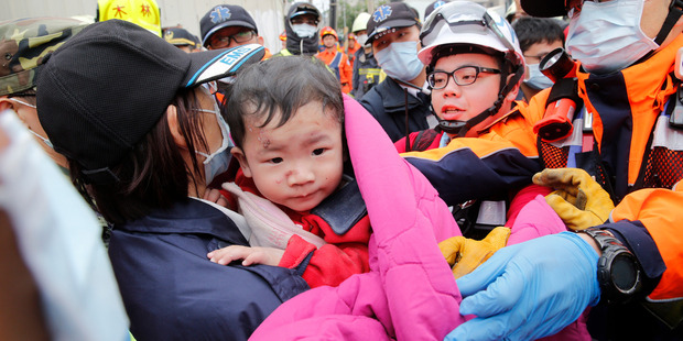 A baby boy is rescued from a collapsed building. Photo / AP