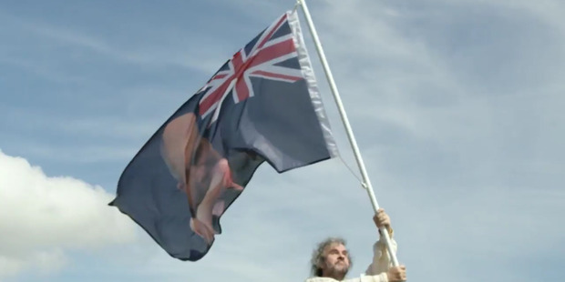 Peter Jackson waves a new New Zealand flag with a picture of Stephen Joyce being hit by a dildo at Waitangi. Photo / Supplied