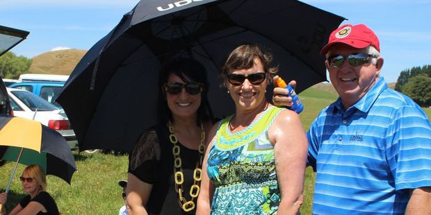 Sari Lamborn (under umbrella) and Sharron and Lloyd Passey picnicking in the carpark before the game. The Lamborns were at the game to see son Tony run on for the Hurricanes. Photo / Christine McKay
