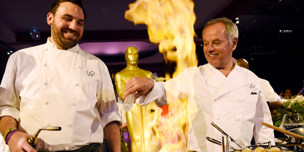 Governors Ball Master Chef Wolfgang Puck, right, and pastry chef Tyler Atwell pour a raspberry liqueur on donuts during the 88th Academy Awards Governors Ball Press Preview. Photo / AP