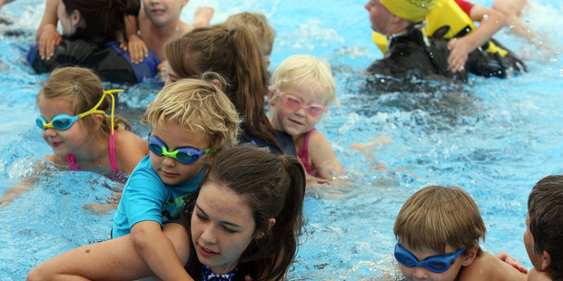 Kids being helped across the pool during last year's Multisports triathlon. PHOTO/FILE