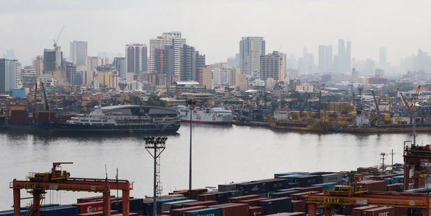 Containers sit stacked next to gantry cranes at Manila International Container Terminal. Photo / SeongJoon Cho