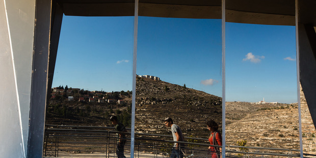 The Jewish settlement of Shiloh, left, a nearby Palestinian village, right, and Israeli visitors are reflected in the windows of the lookout tower at Ancient Shiloh. Photo / Washington Post