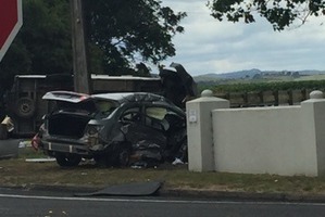 A silver sedan crashed through a thick concrete wall after swiping a campervan which has been left on its side in the background. Photo / Supplied