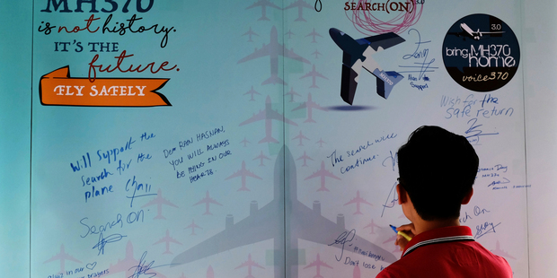 A man writes a condolence message during the Day of Remembrance for MH370 event in Kuala Lumpur, Malaysia.