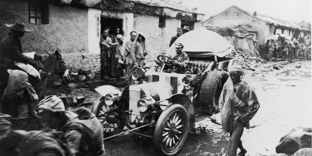 A participant in the Paris to Peking rally in 1907 is pulled along a muddy street. Photo / Getty Images