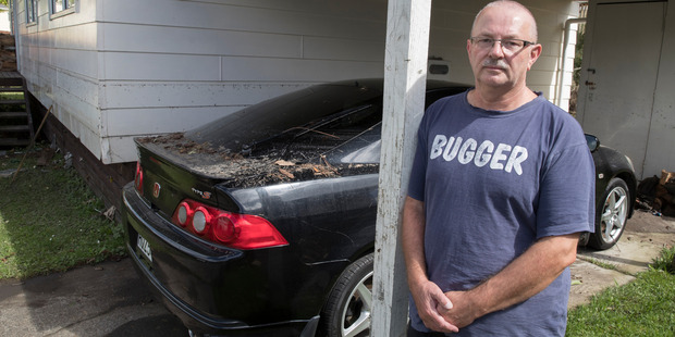 Warren Crowe stands next to his car and house which were flooded in Parker Ave, Titirangi, during yesterday's deluge. Photo / Brett Phibbs