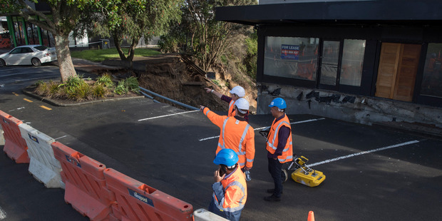 Engineers assess the damage in New Lynn after yesterday's deluge of rain, which caused extensive flooding and damage. Photo / Brett Phibbs
