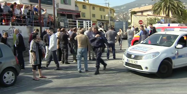 In this image from TV, police cordon off the area as people gather to view the nearby high school, following a shooting in Grasse, southern France. Photo / AP