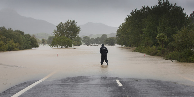 A person makes his way along the flooded section of State Highway 25, at Hikuai near Pauanui last week. Photo / Alan Gibson