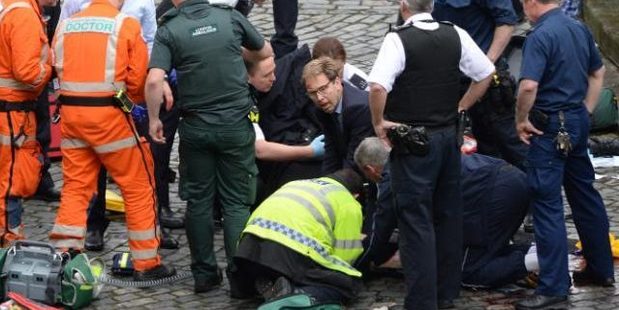 Conservative MP Tobias Ellwood, centre, helps emergency services tend to the injured policeman. Photo / AP