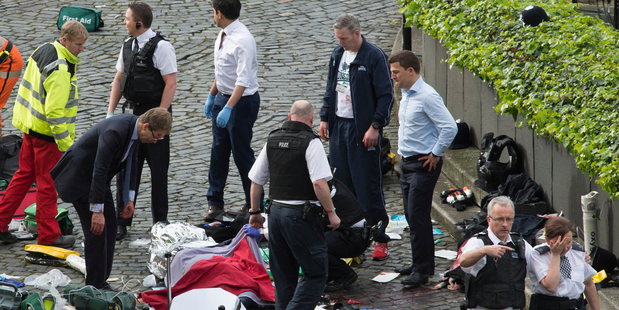 Tobias Ellwood, left, stands amongst the emergency services after assisting the police officer. Photo / AP