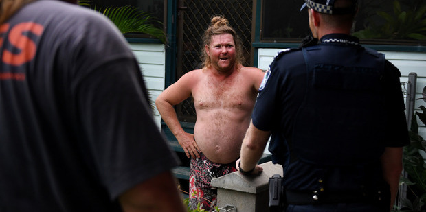 Police and SES advise a resident to evacuate a low lying area of Ayr, south of Townsville. Photo / AAP
