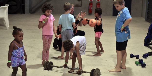 Children entertain themselves in the Ayr temporary cyclone shelter with weight and other gym equipment lying around. Photo/Getty Images