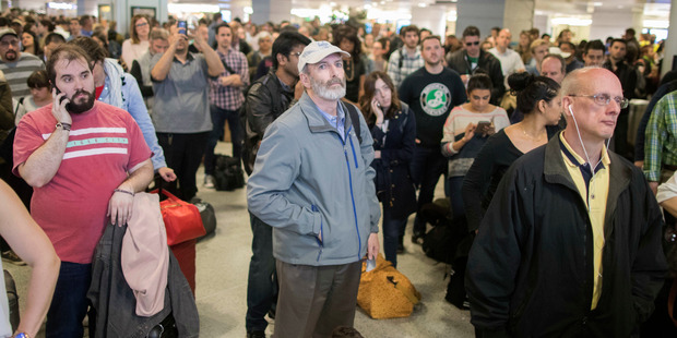 Evening rush hour commuters look at the departures board at Penn Station after a train became stuck in a tunnel for three hours. Photo / AP