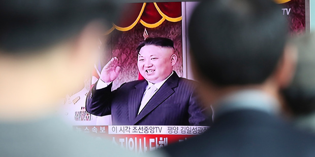People watch a live television program showing North Korean leader Kim Jong Un saluting during a parade in Pyongyang today. Photo / AP