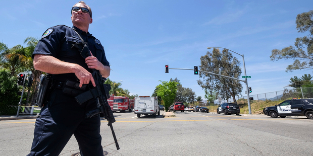 A police office stands guard outside North Park School after a fatal shooting at the elementary school. Photo / AP