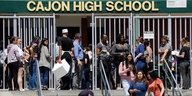 Parents and guardians of North Park Elementary School students wait at Cajon High School to pick up their children. Photo / AP