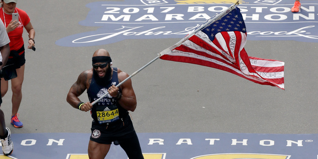 Jose Sanchez, of San Antonio, carries the United States flag across the finish line in the 121st Boston Marathon. Photo / AP