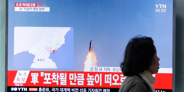 A visitor walks by a TV showing file footage of a North Korea's ballistic missile launch. Photo / AP