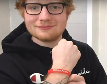 Ed memakai gelang Ollie's Army