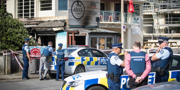Police at the charred remains today of Adey's Place in Piha. Photo / Jason Oxenham