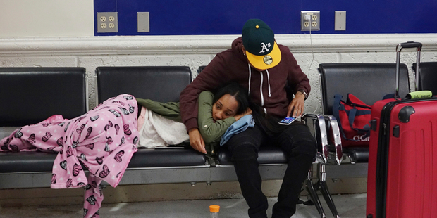 Latreece Smith rests as her friend Tamari Cameron checks flight information at the Fort Lauderdale-Hollywood International Airport. Photo / AP