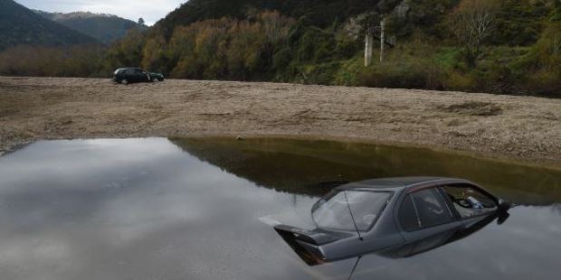 A Nissan Primera sits on the bed of the Taieri River, and a Nissan Sentra lies abandoned at Outram Glen on Wednesday. Photo / Otago Daily Times