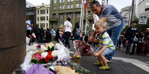 A child lays flowers on the corner of Bourke and Elizabeth Street. Photo / AAP