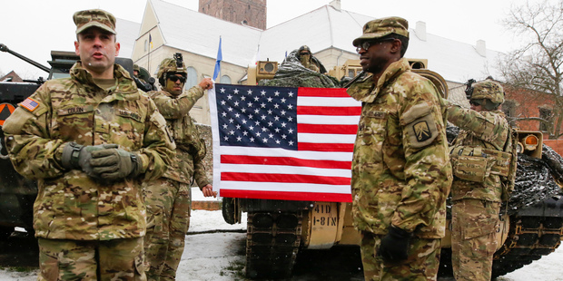 US soldiers hold an American flag as they attend the official welcoming ceremony of the US troops in Zagan, Poland, earlier today. The ceremony comes 23 years after the last Soviet troops left Poland. Photo / AP