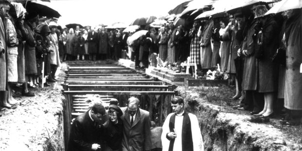 Accompanied by a clergyman, mourners leave the mass grave of the 19 miners killed in the Strongman Mine disaster on January 19, 1967. Photo / New Zealand Herald archive