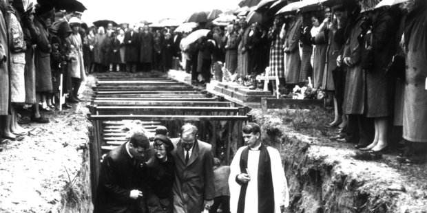 Accompanied by a clergyman, mourners leave the mass grave of those killed in the mining disaster at the Strongman Mine 50 years ago today. Photo / New Zealand Herald Archives