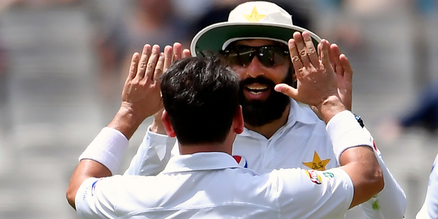 Pakistan's Yasir Shah, front, is congratulated by captain Misbah-ul-Haq after capturing the wicket of Australia's Matthew Renshaw. Photo / Andy Brownbill