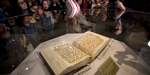 Visitors look at an ancient copy of the Quran, Islam's holy book, written on parchment and dated to the 8th century Umayyad period. Photo / AP