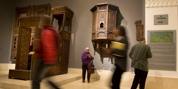 Visitors walk past a wooden pulpit brought from the mosque of Tatar al-Higaziya 1348-1360 A.D. Photo / AP