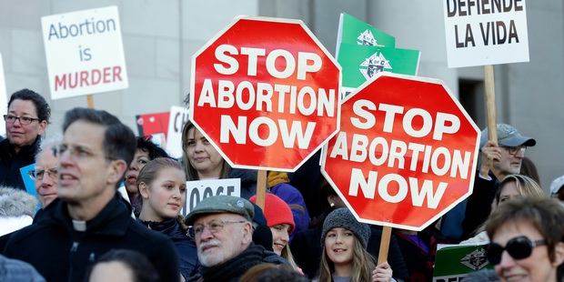 Participants in an anti-abortion rally hold signs that read "Stop Abortion Now" as they listen to speakers, at the Capitol in Olympia. Photo / AP