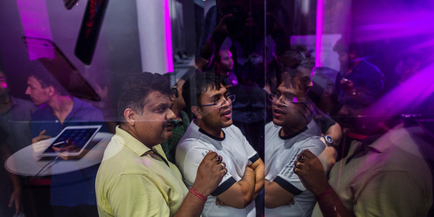Customers wait in line outside an iZenica store prior to a midnight launch event for the Apple iPhone in New Delhi, India. Photo / Bloomberg