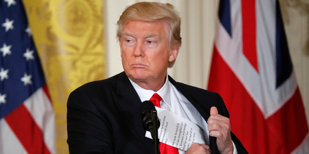 President Donald Trump tucks away his notes near the conclusion of a joint news conference with British Prime Minister Theresa May. Photo / AP