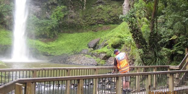 A Waikato Regional Council staff member tests the "unusual" water colour of Bridal Veil Falls yesterday. Photo / Waikato Regional Council