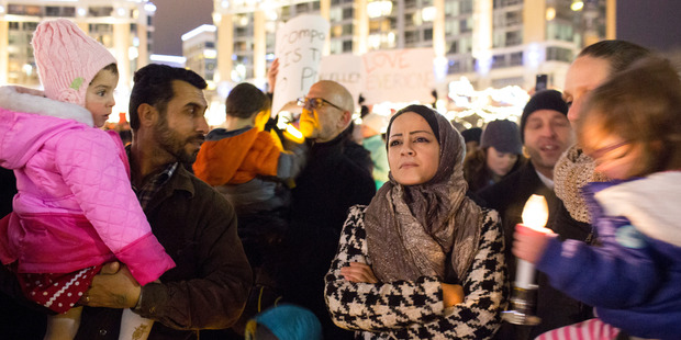 Fatema Aljasen, centre right, and her husband Ahmad, holding their daughter Ahed, listen during the vigil. Photo / The Washington Post