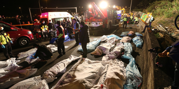 Bodies are covered at the scene of a crash where a bus collided with a car on a highway in Taipei, Taiwan. Photo / AP
