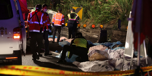 Bodies are covered as emergency services attend the scene of a crash where a bus collided with a car on a highway in Taipei, Taiwan. Photo / AP