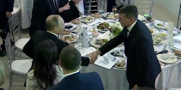 In this image made from a video taken on December 10, 2015 Donald Trump's former National Security Adviser Michael Flynn, right, shakes hands with Vladimir Putin.