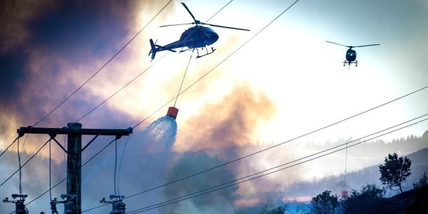 Helicopters empty monsoon buckets over a house on Early Valley Rd in Christchurch's Port Hills. Christchurch Star photo / Martin Hunter