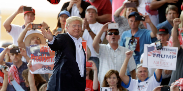 President Donald Trump throws a hat into the crowd during the Make America Great Again rally. Photo / AP