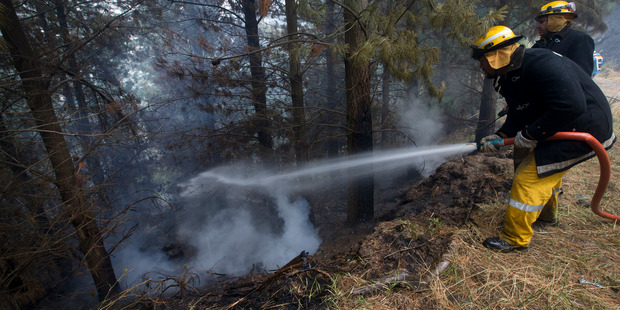 A firefighter dampening down hotspots last week. Photo / Alan Gibson