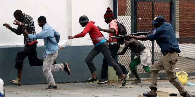 A metro police officer fires rubber bullets at anti-immigrant protesters in Pretoria, South Africa, at the weekend. Photo / AP