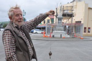 Max Dowell lines up his plumb-bob against the pioneer statue. Photo / Janna Sherman
